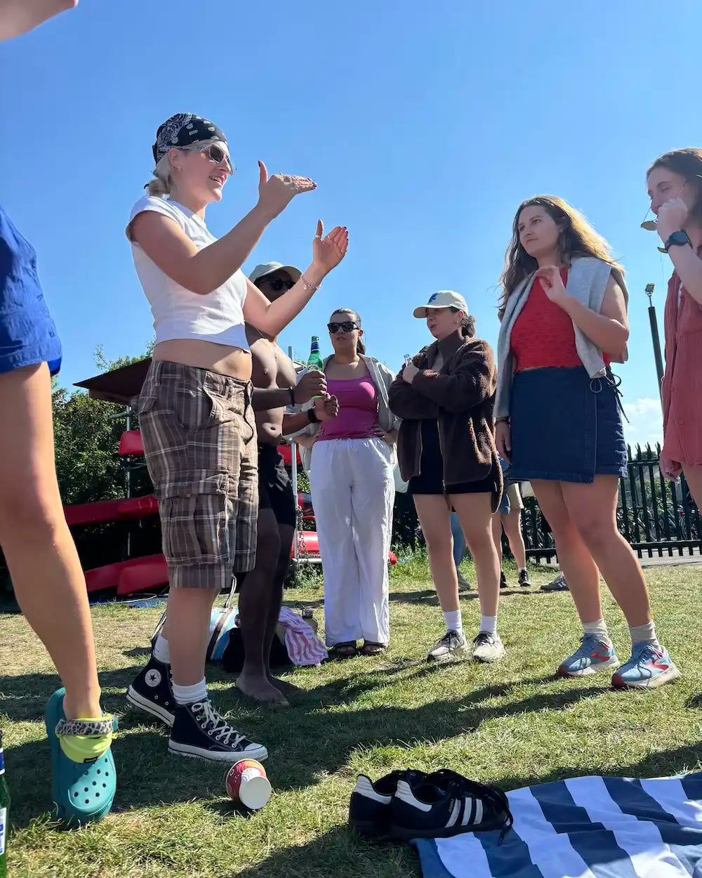Group of people standing on grass with a clear blue sky socialising after a London swim club event